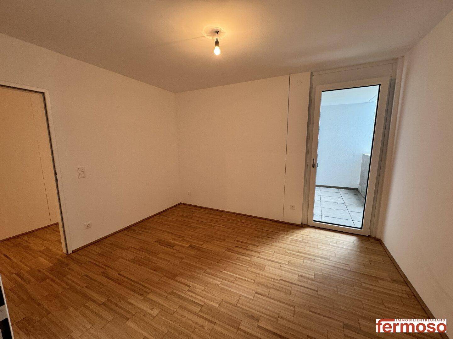 Schlafzimmer mit Parkettboden und Zugang zu einem Außenbereich, ideal für Ruhe und Entspannung.