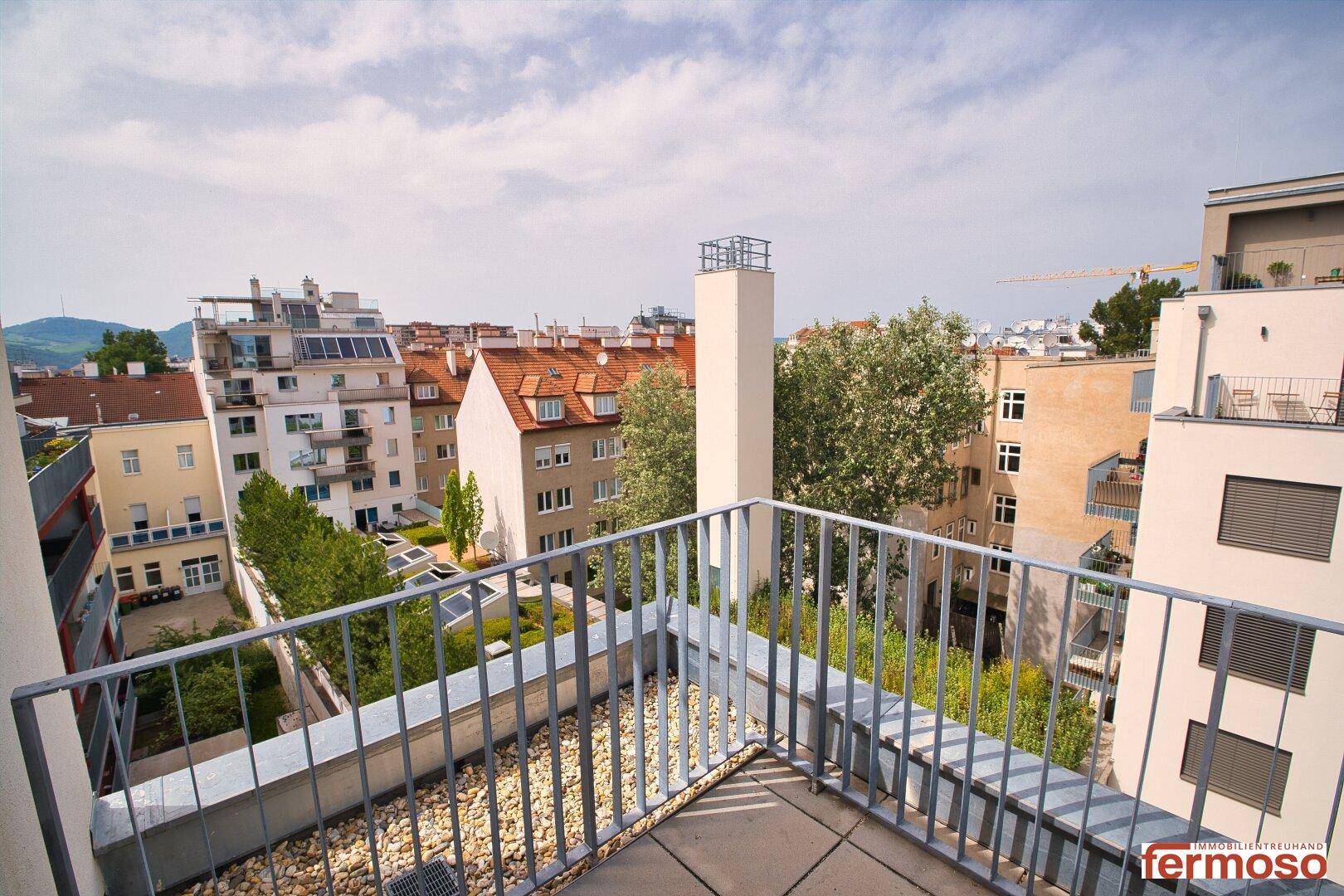 Geräumiger Balkon mit Metallgeländer und Blick auf die umliegenden Gebäude.