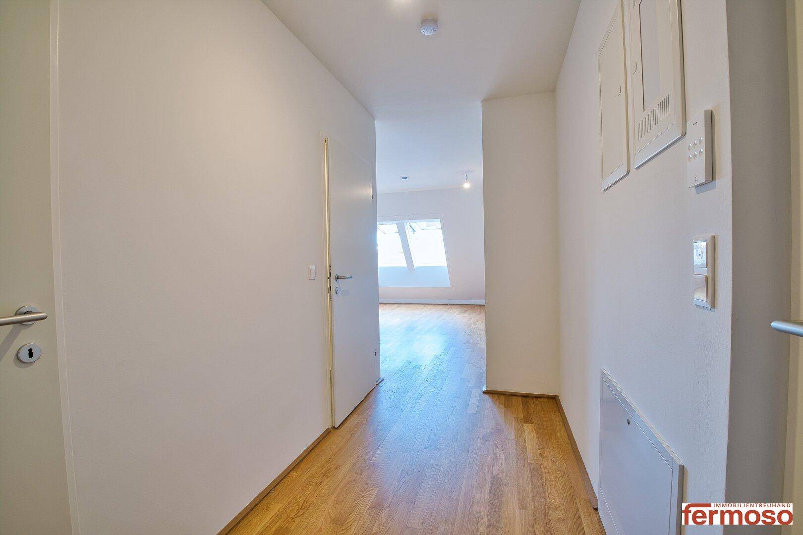 Heller Flur mit Holzparkettboden, der zu weiteren Räumen führt.