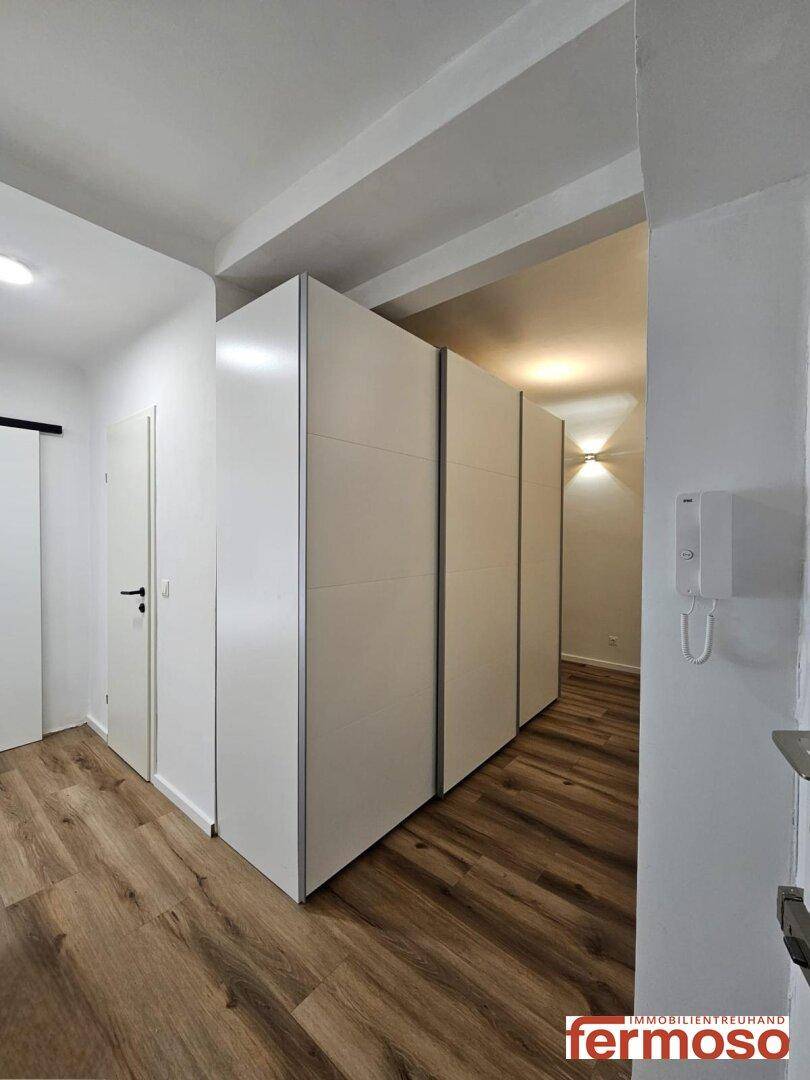 Heller Flur mit Einbauschränken und Holzboden, bietet viel Stauraum.