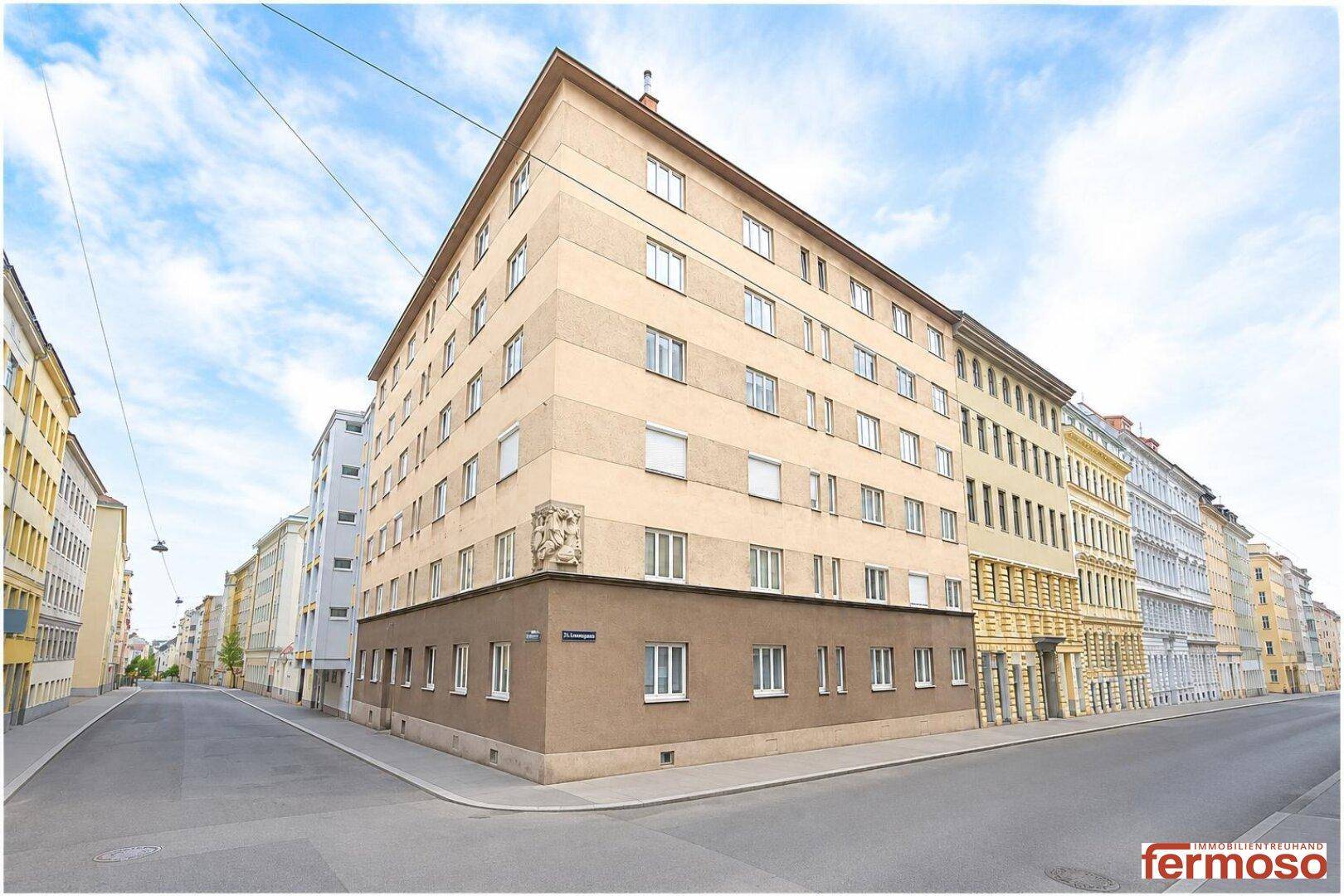 Eckgebäude in städtischer Umgebung mit klassischer Architektur und mehreren Etagen.