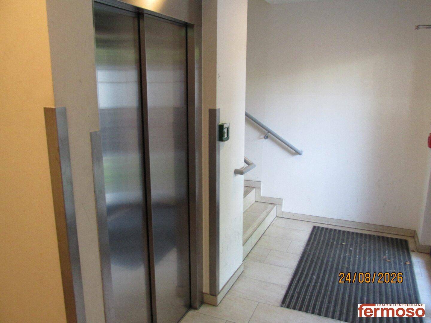 Heller Flur im Gebäude mit Aufzug und Treppenhaus, gut beleuchtet und funktional gestaltet.