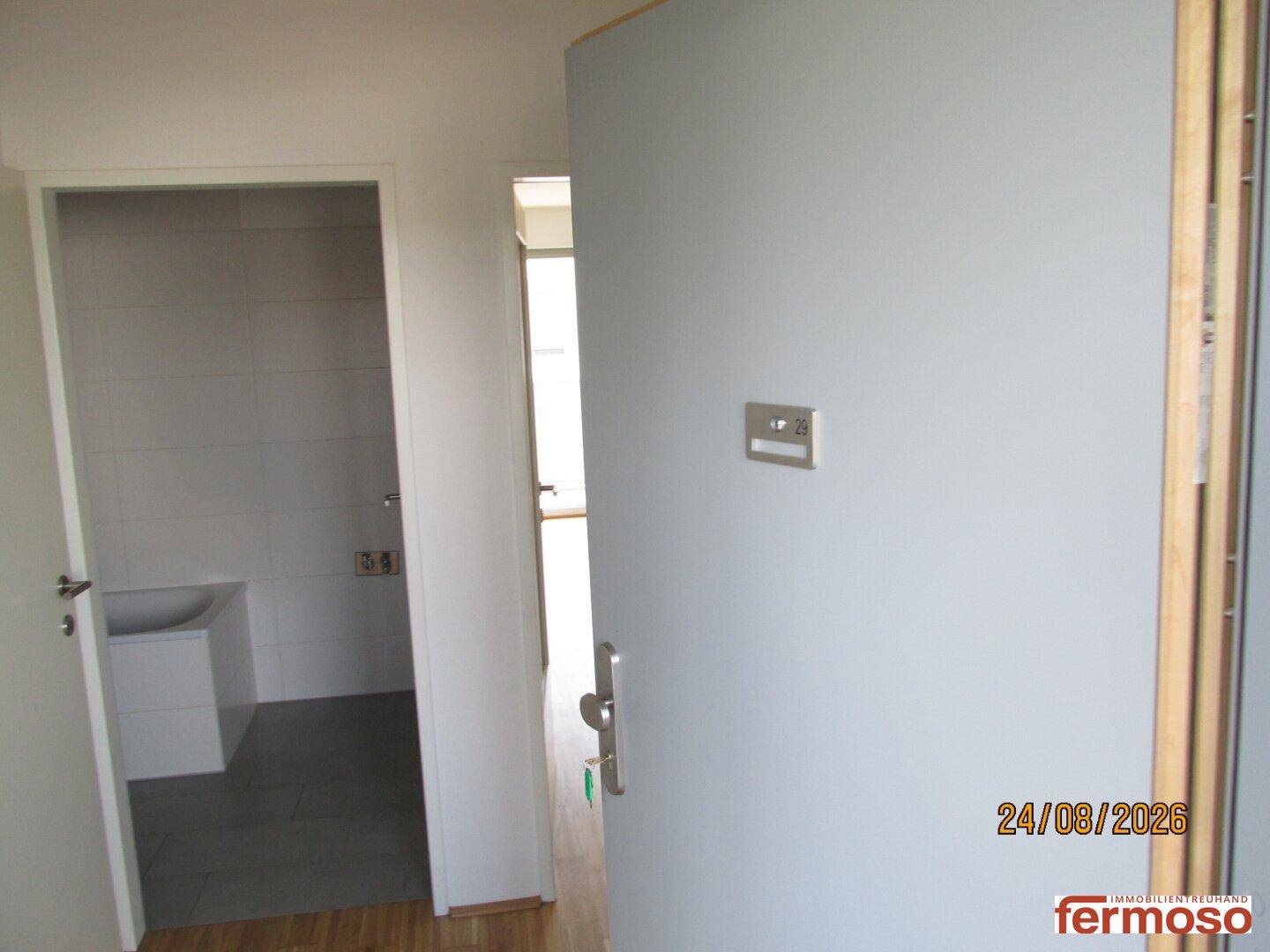 Eingangsbereich einer Wohnung mit offener Tür und Blick in ein Badezimmer.