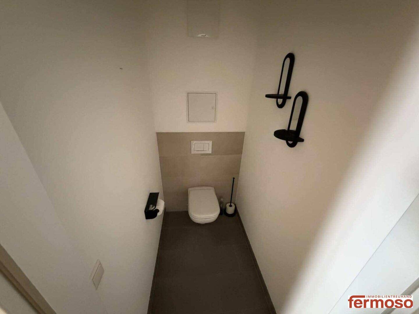 Kleines Gäste-WC mit wandhängender Toilette und zweifarbigen Fliesen.