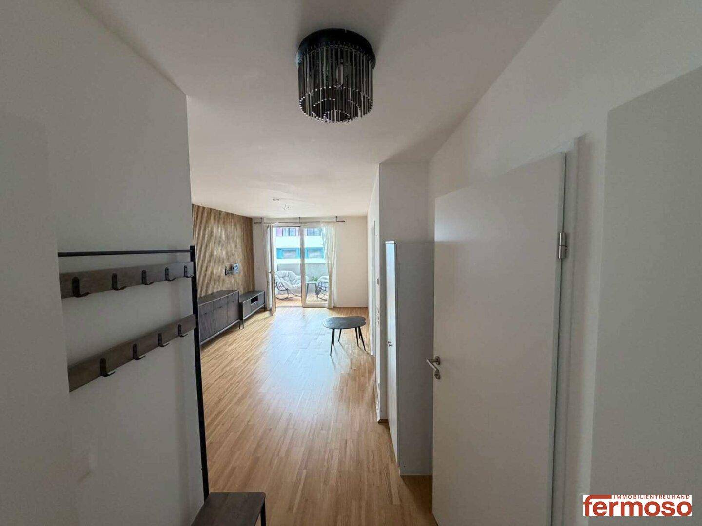 Heller Flur mit Holzboden, Garderobe und Blick in den offenen Wohnbereich.