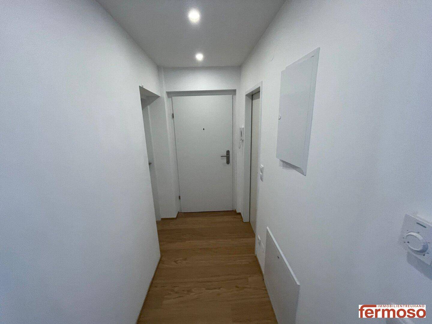 Heller Flur mit Holzboden und mehreren Türen, der zu den verschiedenen Räumen führt.