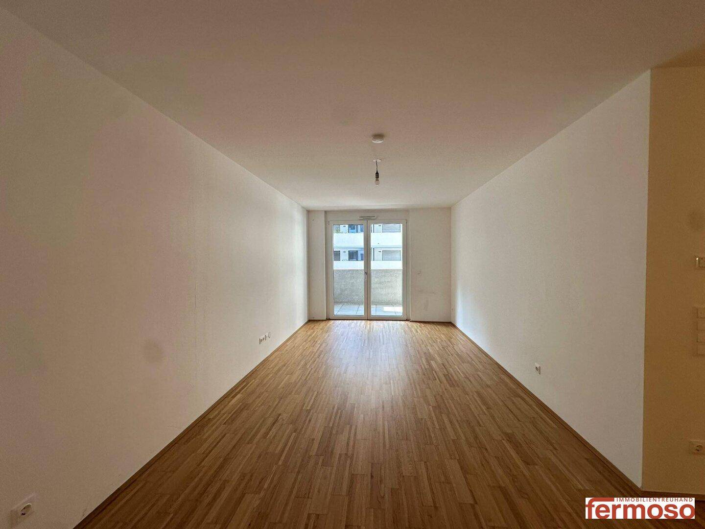Geräumiges Wohnzimmer mit Parkettboden und direktem Zugang zu einem Balkon.