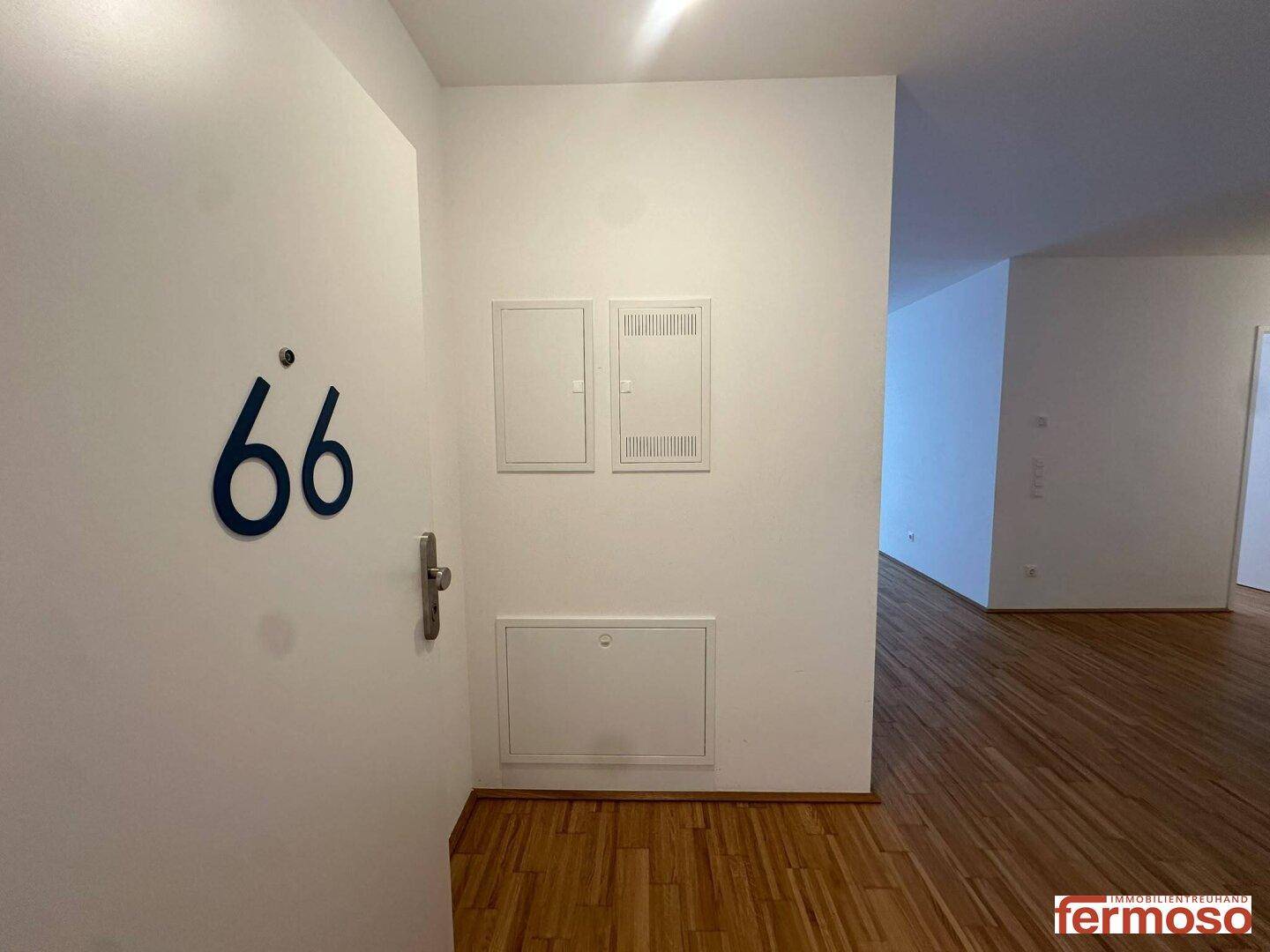 Eingangsbereich mit Hausnummer 66, Parkettboden und Zugang zu den Wohnräumen.