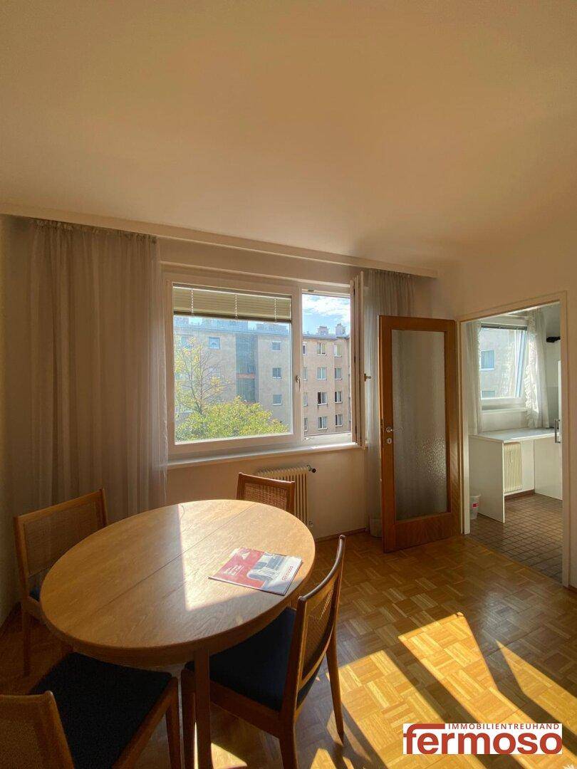 Heller Essbereich mit Holztisch, Stühlen und Blick in die angrenzende Küche.
