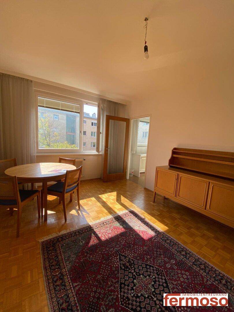 Heller Wohn- und Essbereich mit Parkettboden, Esstisch und großem Fenster mit Ausblick.