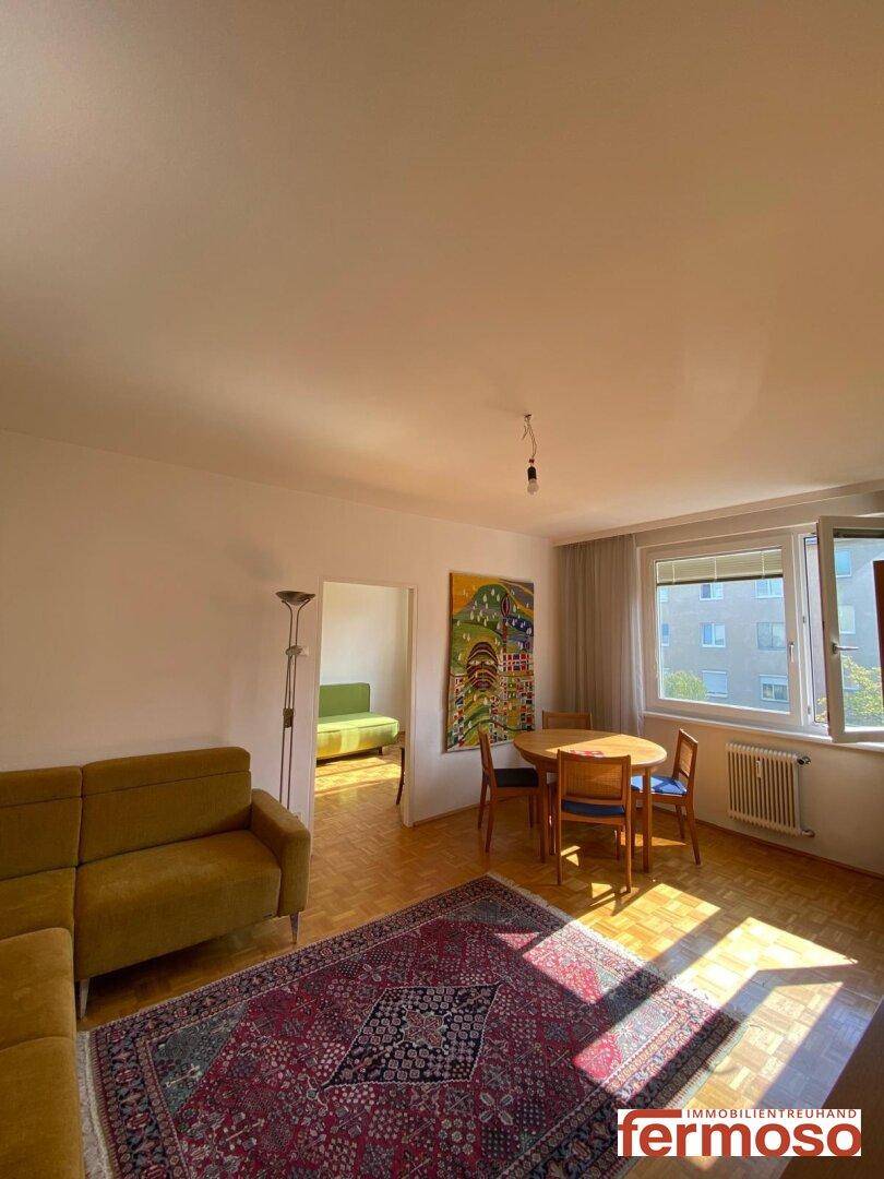 Sonniges Wohn- und Esszimmer mit Parkettboden, Ecksofa und Esstisch für gemütliche Abende.