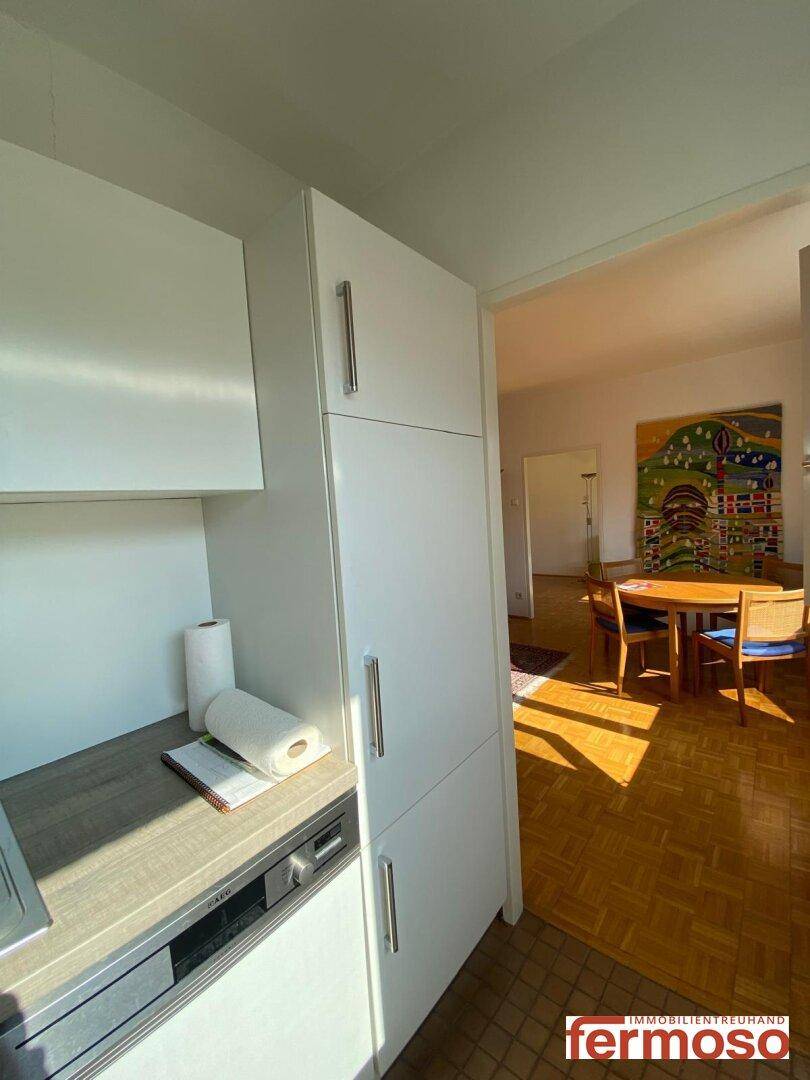 Küche mit weißen Schränken und Blick auf den angrenzenden Wohn- und Essbereich.