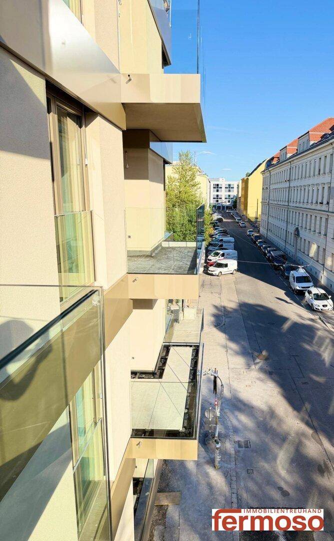 Blick von einem Balkon auf die darunterliegende Straße und die umliegenden Gebäude.