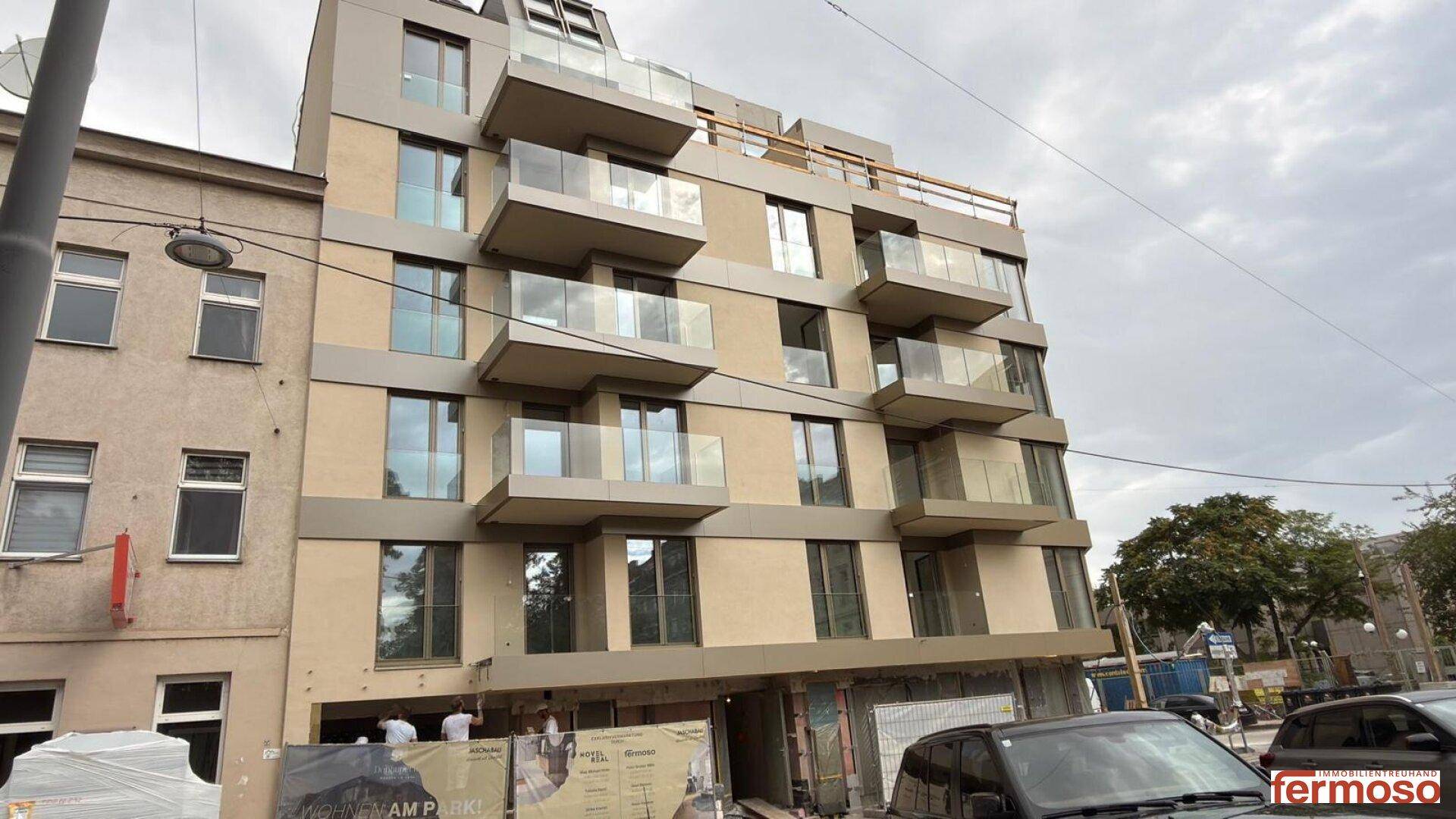 Moderner Neubau mit mehreren Balkonen und großen Fenstern in urbaner Umgebung.