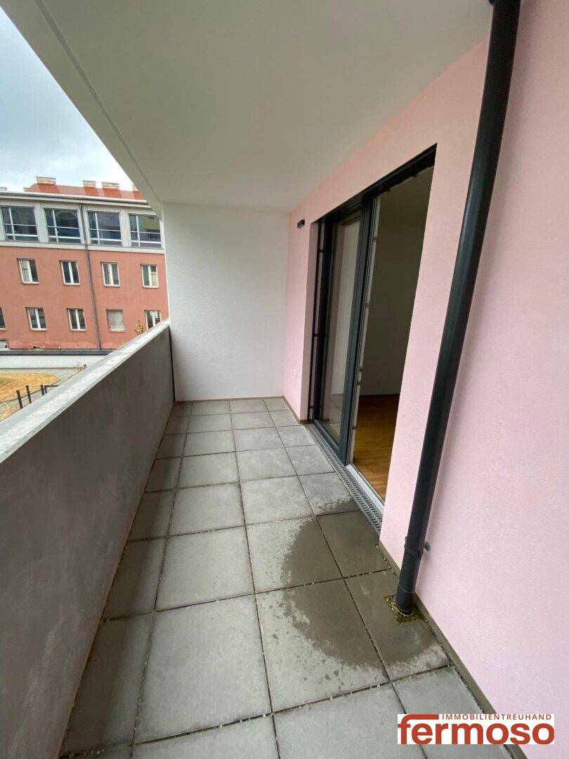 Geräumiger Balkon mit Zugang durch eine Glasschiebetür und Blick auf die Nachbarschaft.