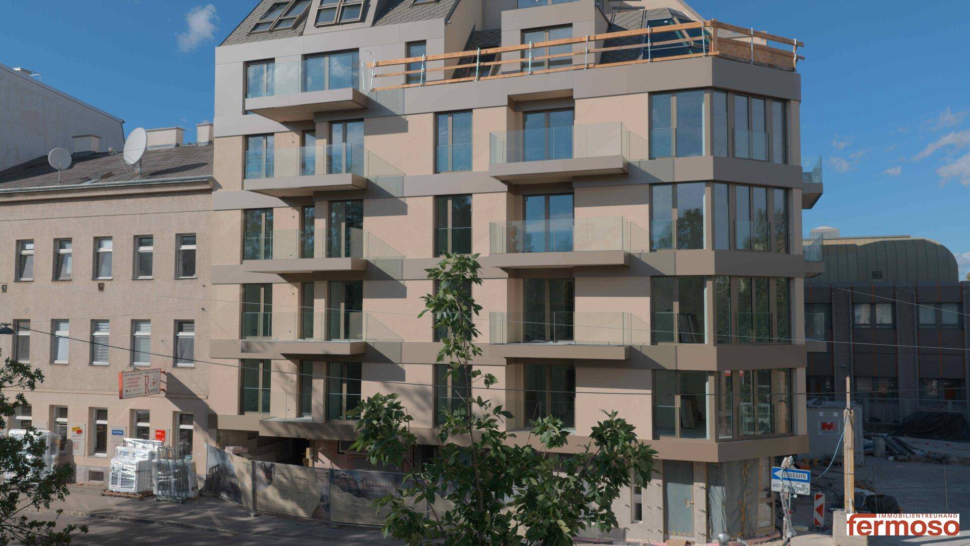 Moderne Wohngebäude-Fassade mit Balkonen und großen Fenstern unter blauem Himmel.