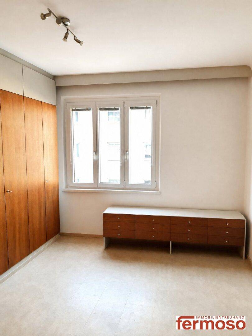 Helles Schlafzimmer mit großen Fenstern und eingebauten Holzschränken, bereit zur Möblierung.
