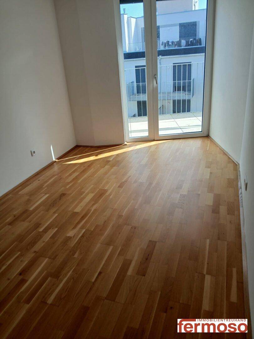 Leerer Raum mit Parkettboden und Zugang zum Balkon, vielseitig nutzbar.