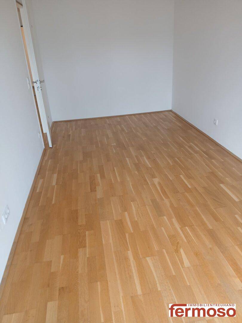 Leeres Schlafzimmer mit hellem Parkettboden, bereit für individuelle Einrichtung.