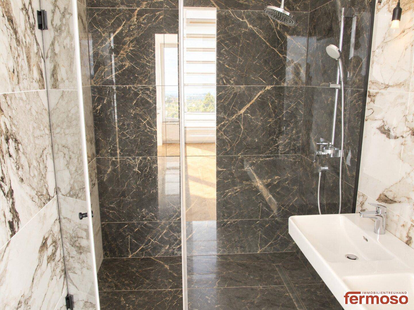 Modernes Badezimmer mit dunklen Marmorfliesen, begehbarer Dusche und elegantem Waschbecken.