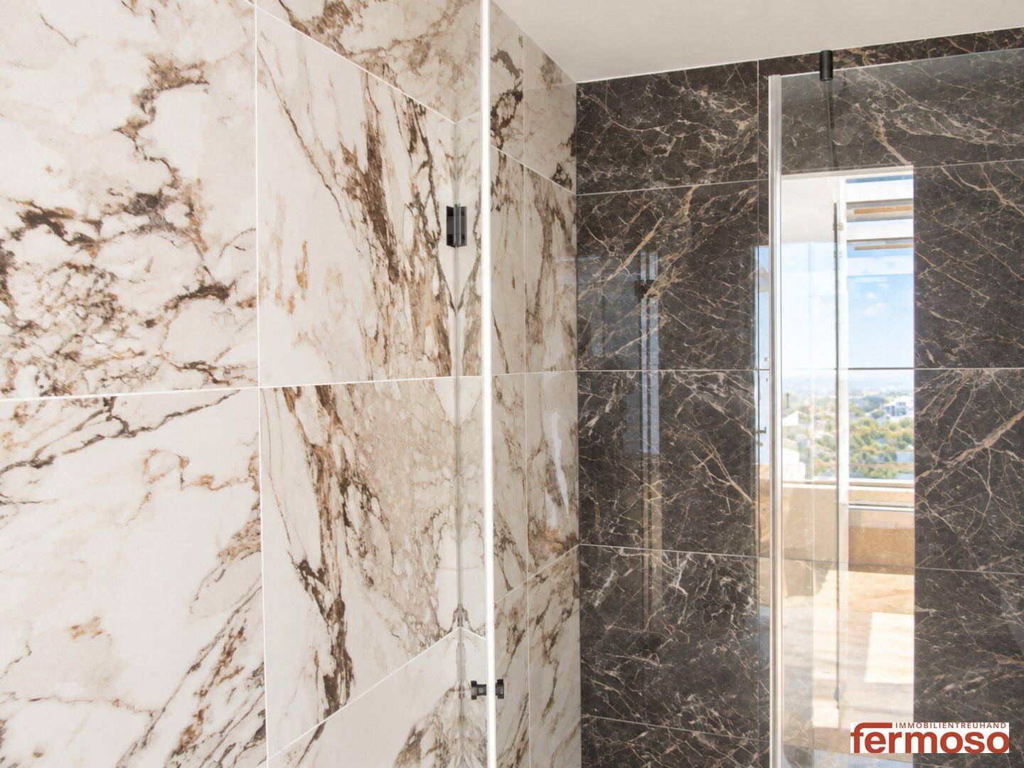 Detailansicht der hochwertigen Marmorfliesen im modernen Badezimmer mit Glasdusche und eleganten Oberflächen.