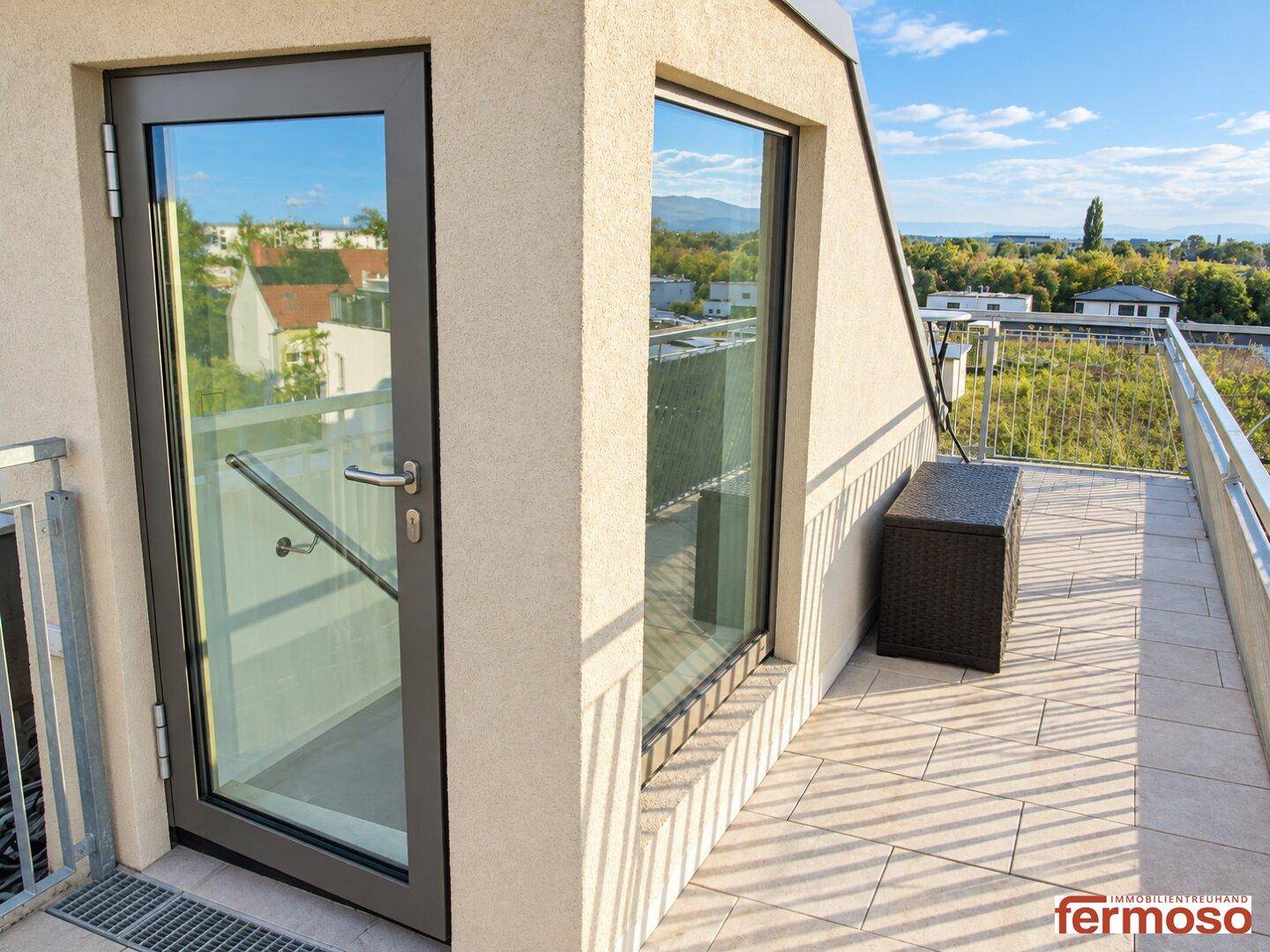 Zugang zur Terrasse mit großen Glasfenstern und Tür, die einen weiten Blick in die Natur bieten.