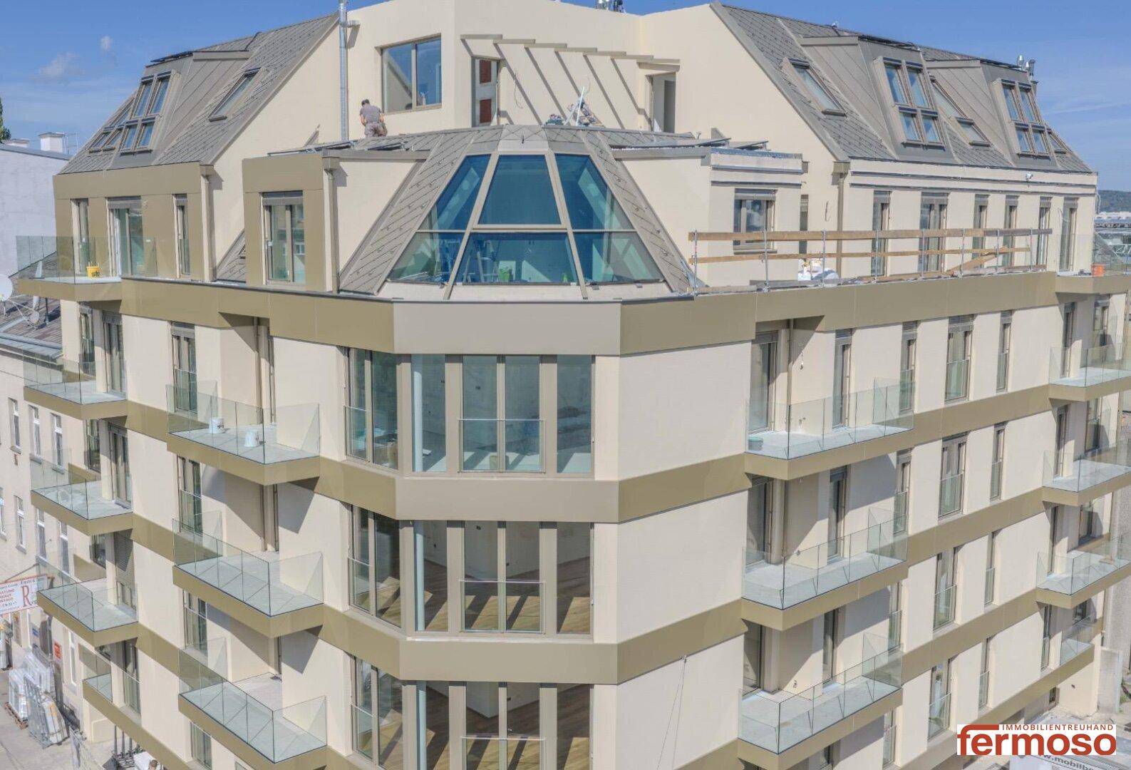 Luftaufnahme eines modernen Wohngebäudes mit Dachterrassen und großen Glasflächen.