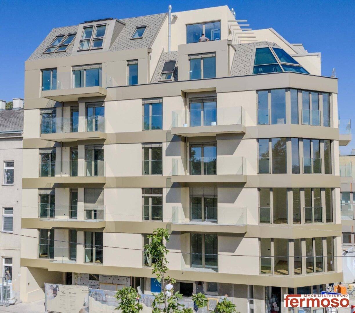 Gesamtansicht des modernen Neubaus mit Balkonen und großen Fensterfronten.