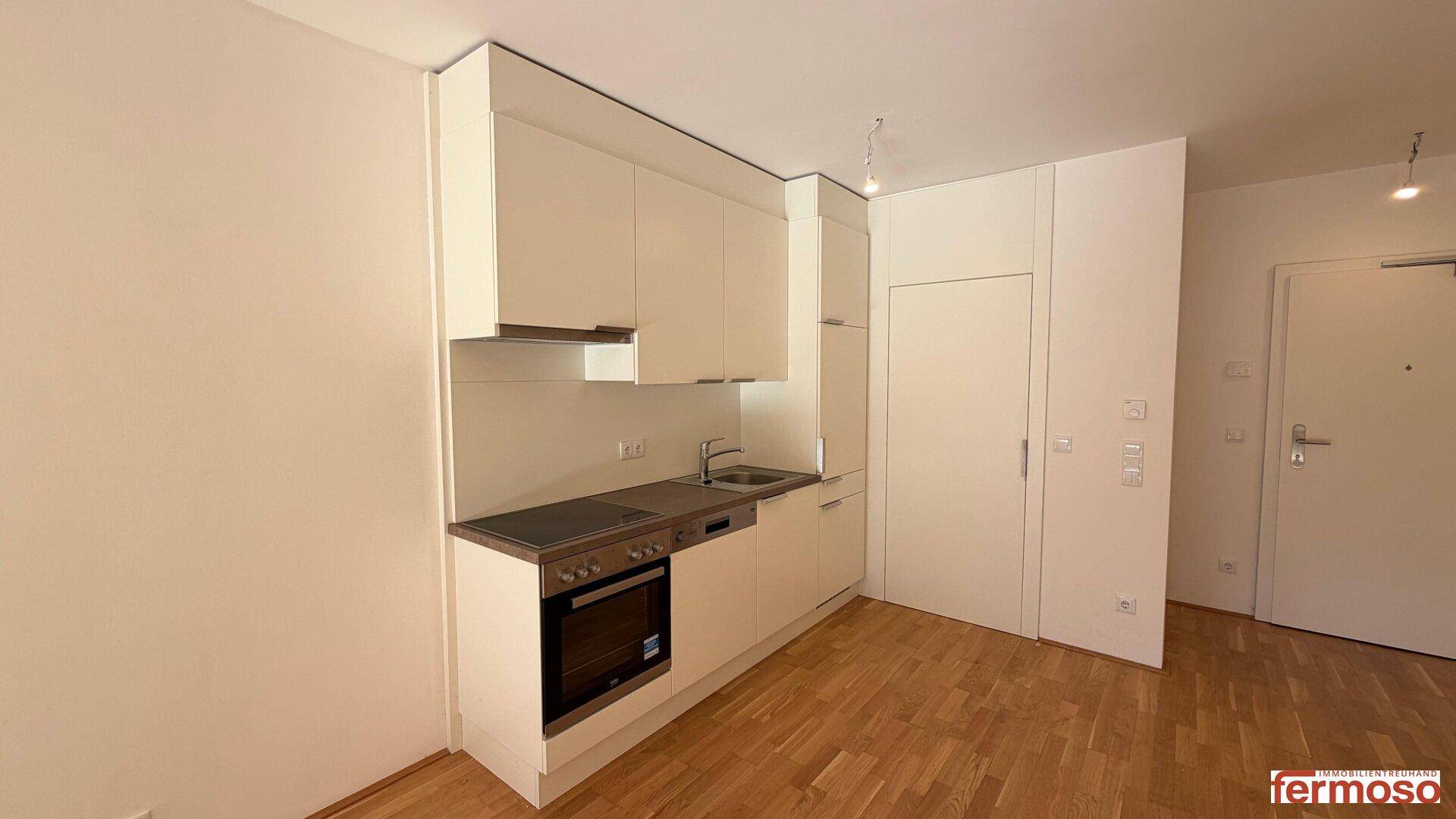 Moderne Küchenzeile mit weißen Schränken, integriertem Herd, Backofen und Spülmaschine.