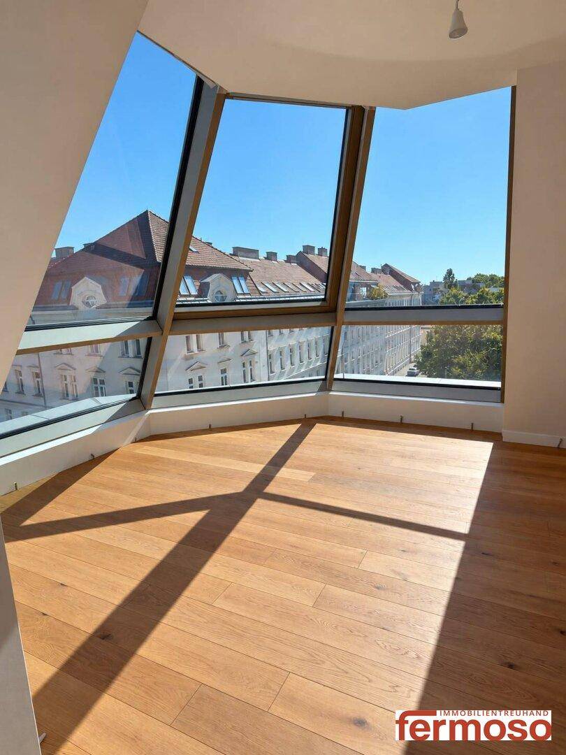 Heller Wohnraum mit Eichenparkett und großen, schrägen Fensterfronten mit Stadtblick.