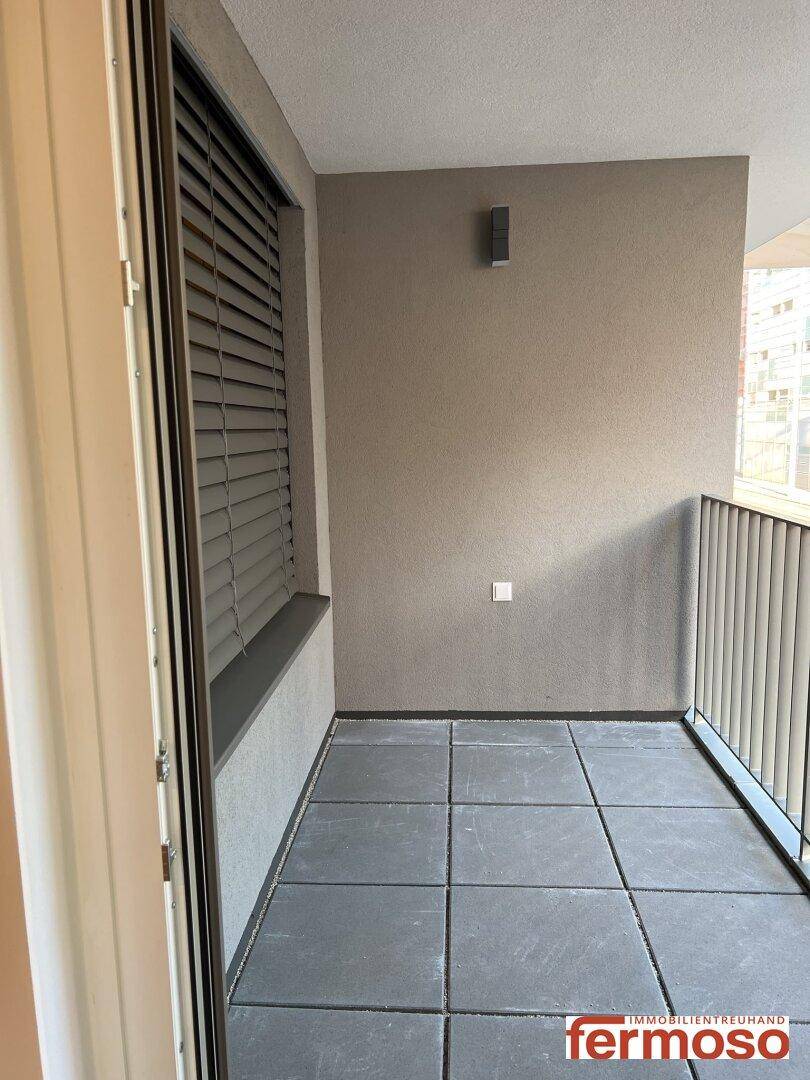 Leerer Balkon mit Fliesenboden und Metallgeländer, bereit zur individuellen Gestaltung.