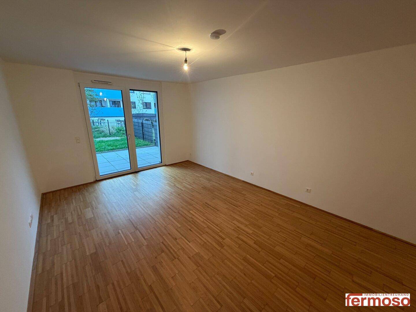 Helles Zimmer mit Parkettboden und großem Zugang zu einem privaten Außenbereich.