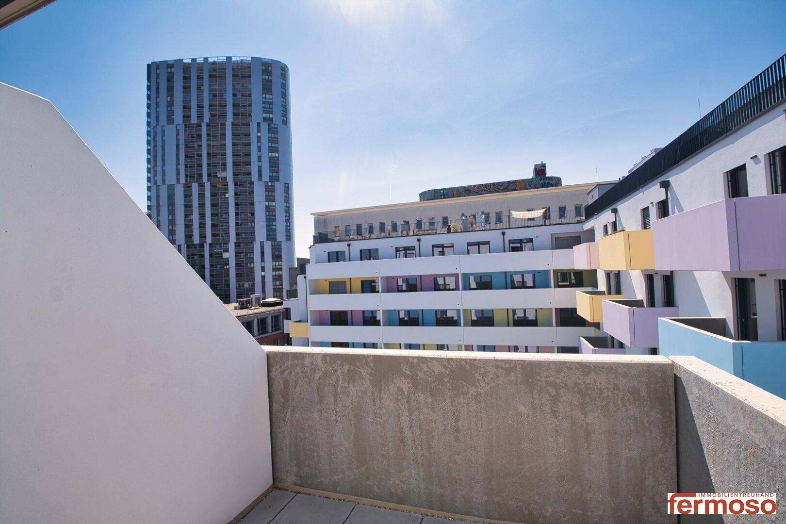 Balkon mit Blick auf die umliegenden Gebäude und den blauen Himmel.
