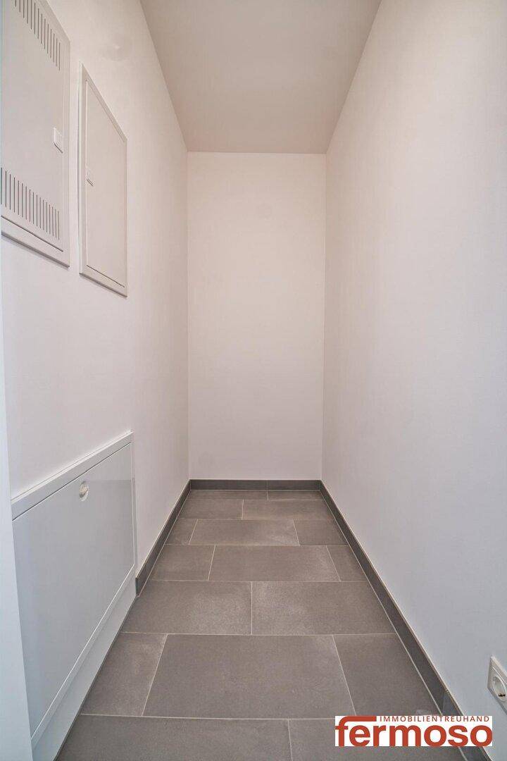 Schmaler Abstellraum mit Fliesenboden und weißen Wänden.