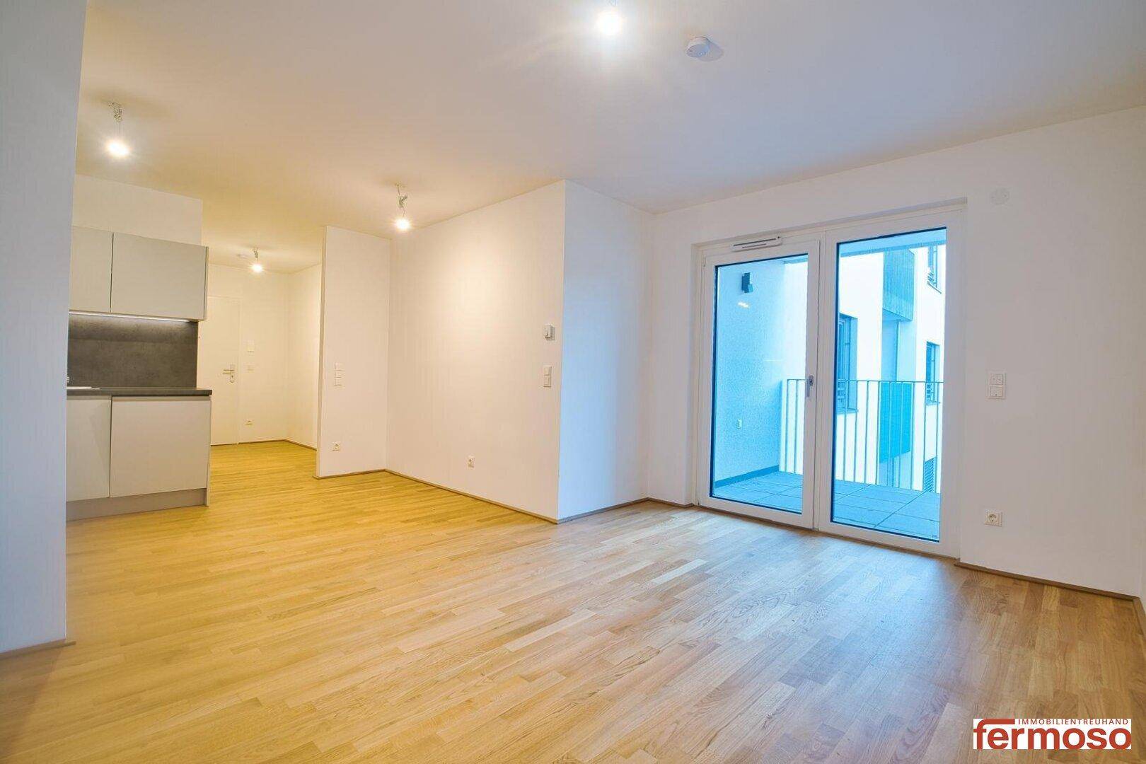 Heller Wohnbereich mit Holzboden und Zugang zu einem Balkon.