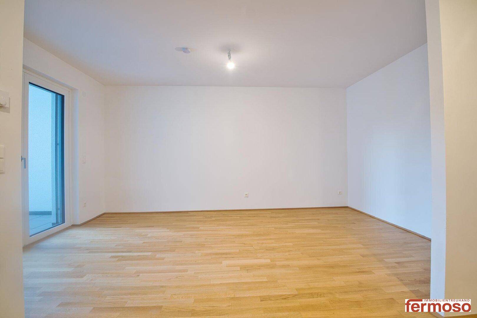 Helles Schlafzimmer mit Holzboden und Zugang zu einem Außenbereich.