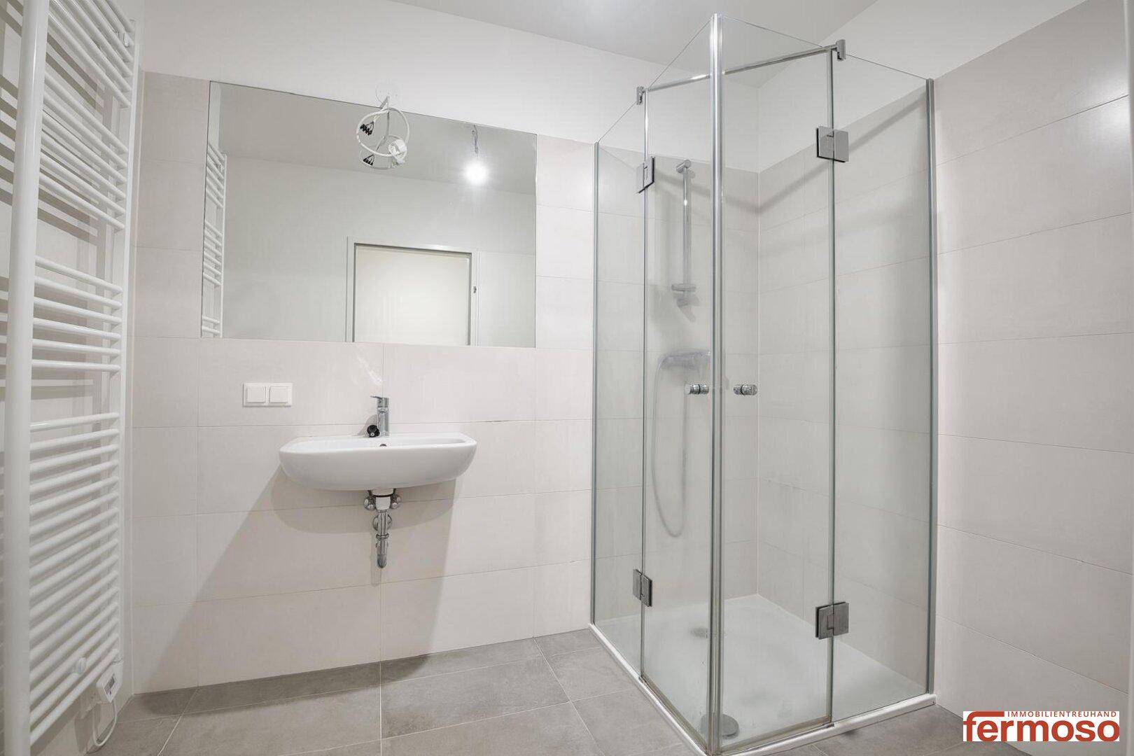 Modernes Badezimmer mit Duschkabine, Waschbecken und Handtuchheizkörper.