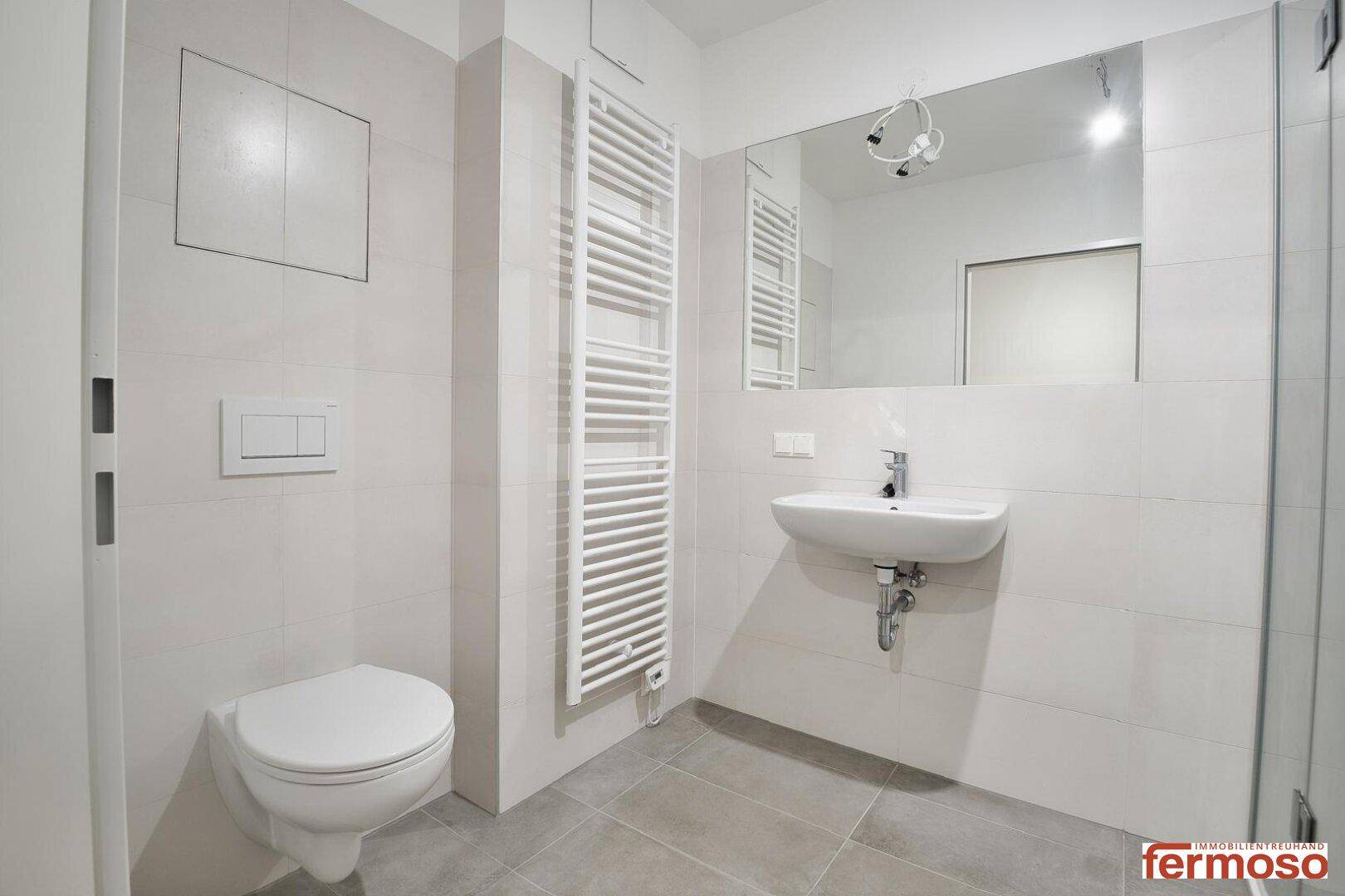 Helles Badezimmer mit WC, Waschbecken und modernem Handtuchheizkörper.