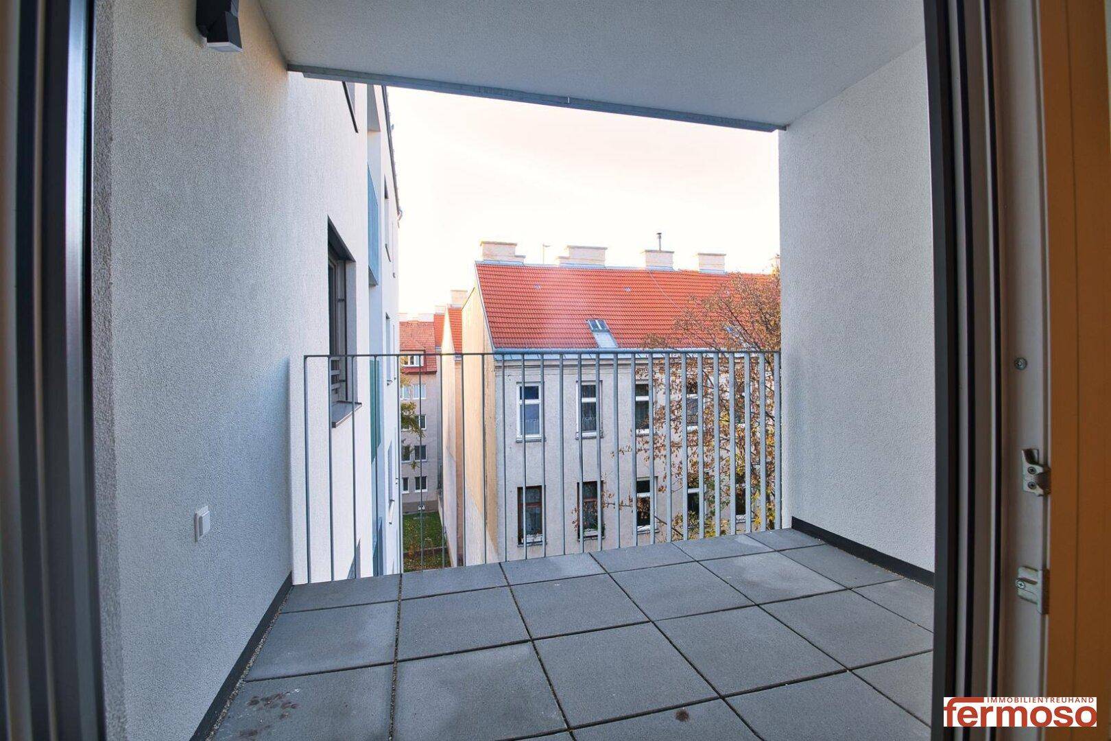 Geräumiger Balkon mit Fliesenboden und Blick auf die umliegenden Gebäude.