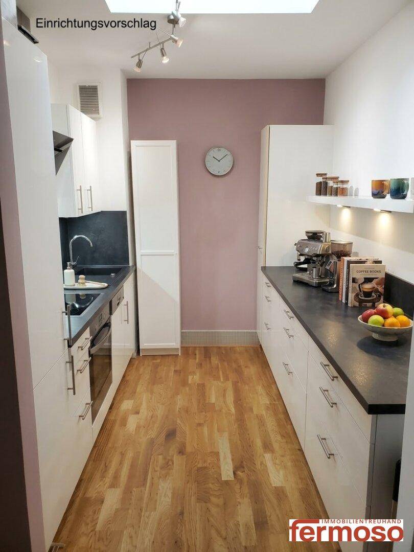 Funktionale Küche mit weißen Schränken, dunkler Arbeitsplatte und Holzboden als Einrichtungsvorschlag.