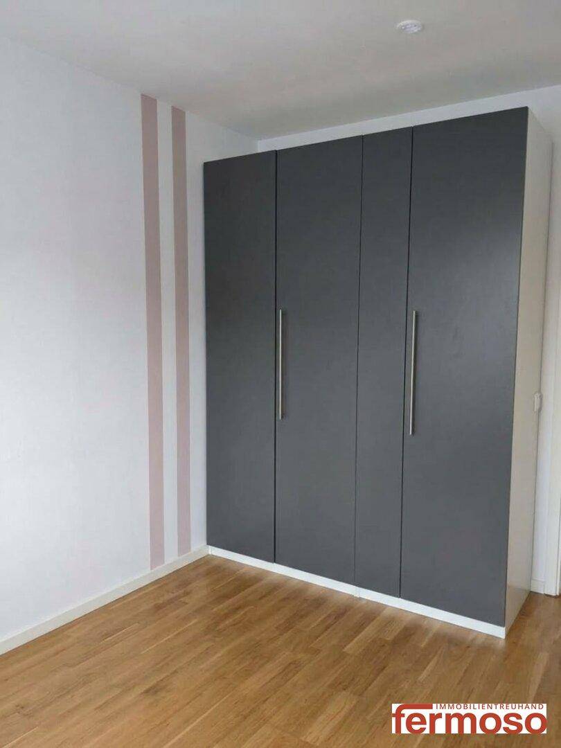 Schlafzimmer mit integriertem, modernem Kleiderschrank und hellem Holzboden.