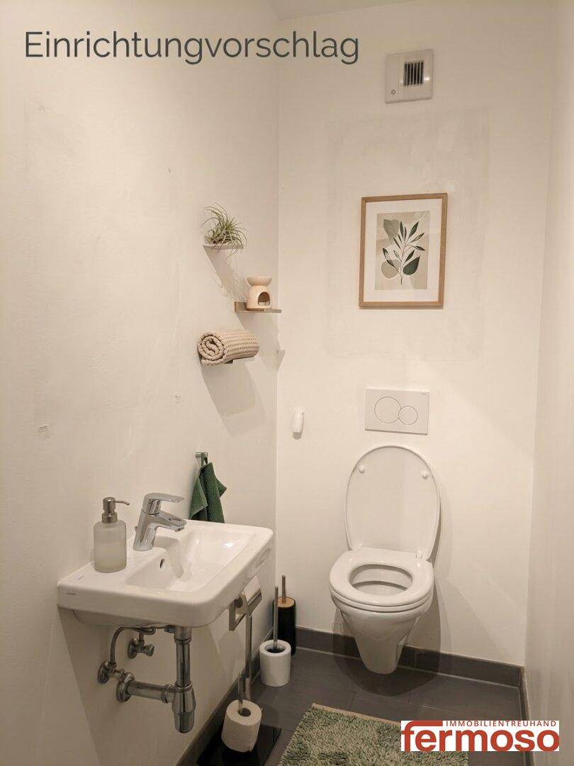 Dekoriertes Gäste-WC mit Wand-WC, Waschbecken und dunklen Bodenfliesen als Einrichtungsvorschlag.
