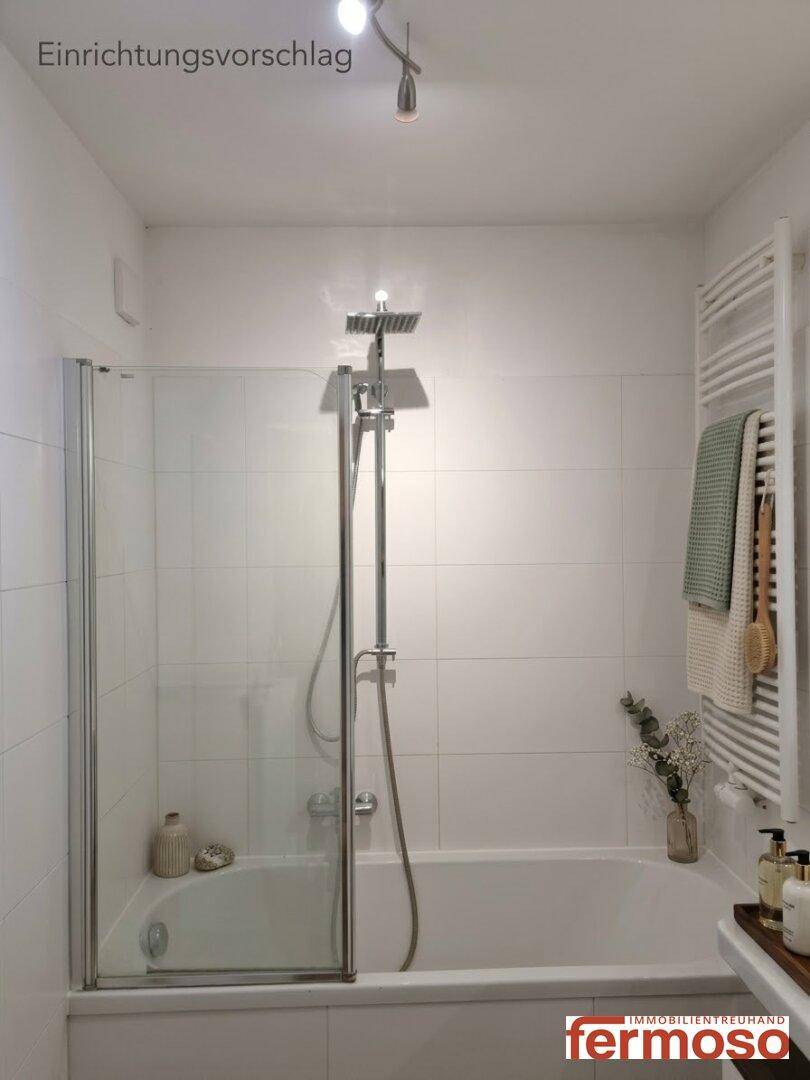 Dekoriertes Badezimmer mit Badewanne, Duschabtrennung und weißer Fliesenverkleidung als Einrichtungsvorschlag.