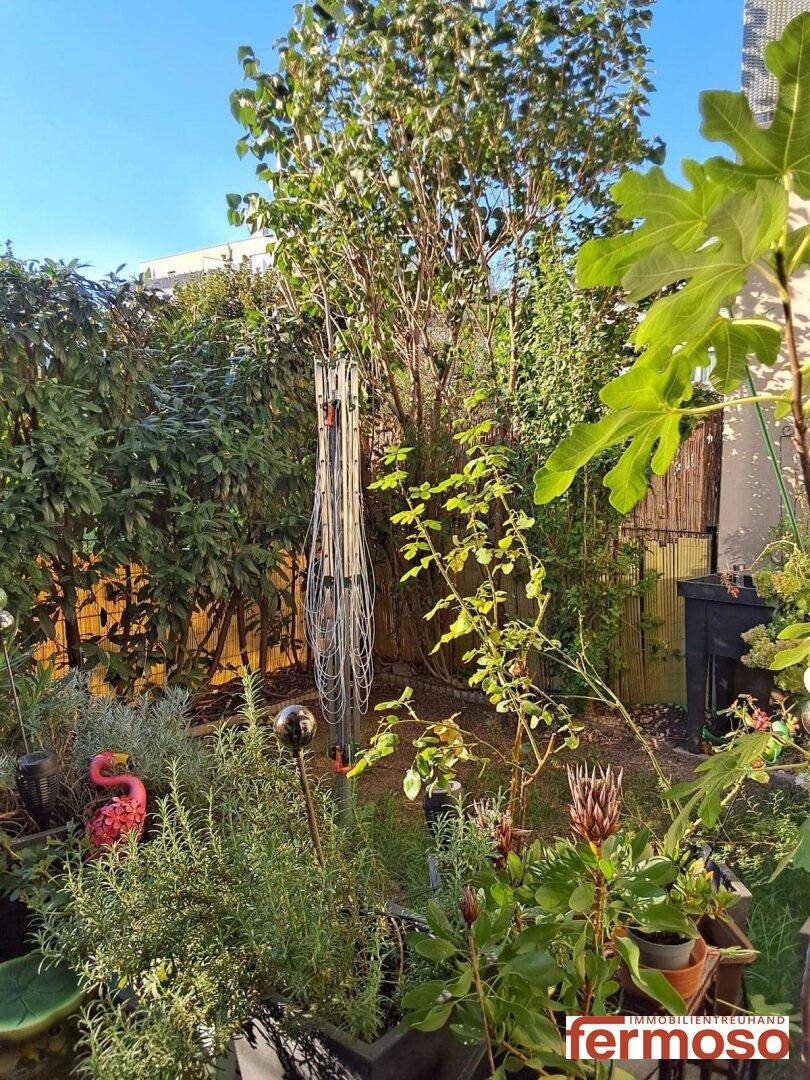 Üppiger Gartenbereich mit verschiedenen Pflanzen, Sträuchern und einem Baum, der Privatsphäre bietet.