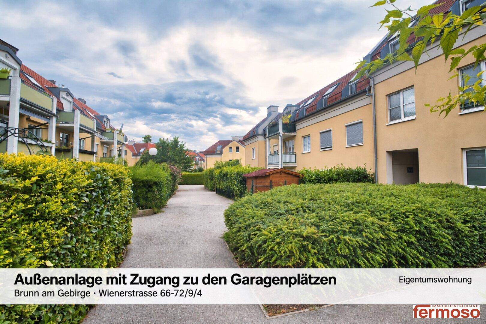 Außenanlage der Wohnanlage mit gepflegten Hecken, Gehwegen und Zugang zu den Garagenplätzen.