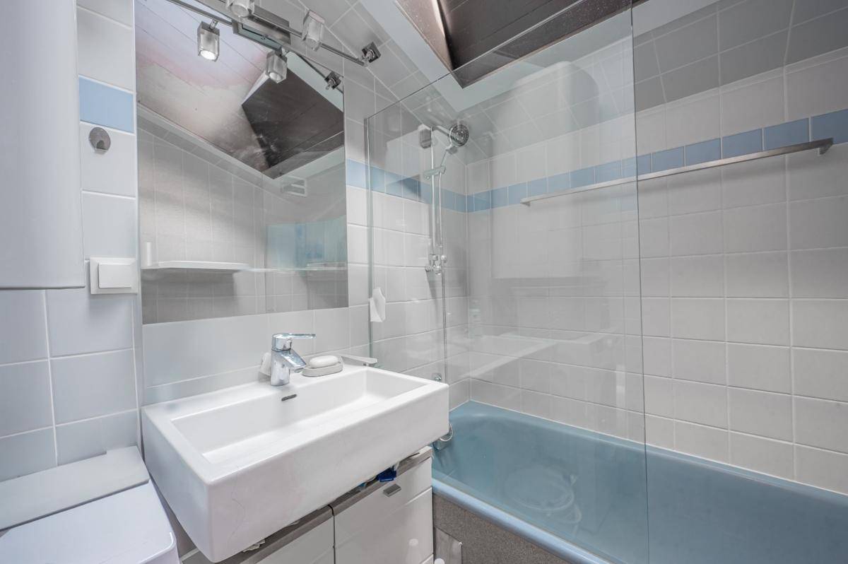 Kleines Badezimmer mit blauen Fliesen, einer Badewanne und einem einzelnen Waschbecken.