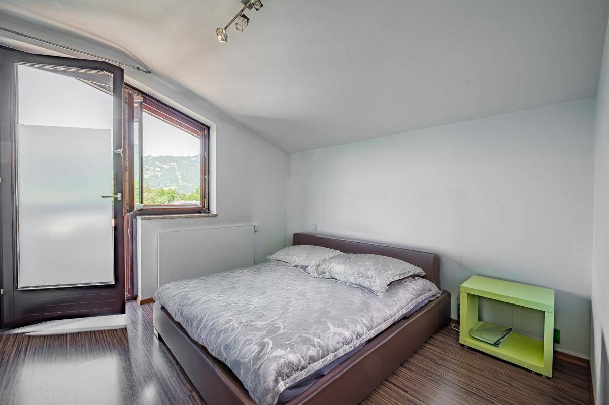 Schlafzimmer mit Holzboden, Doppelbett und Zugang zu einem Balkon mit Bergblick.