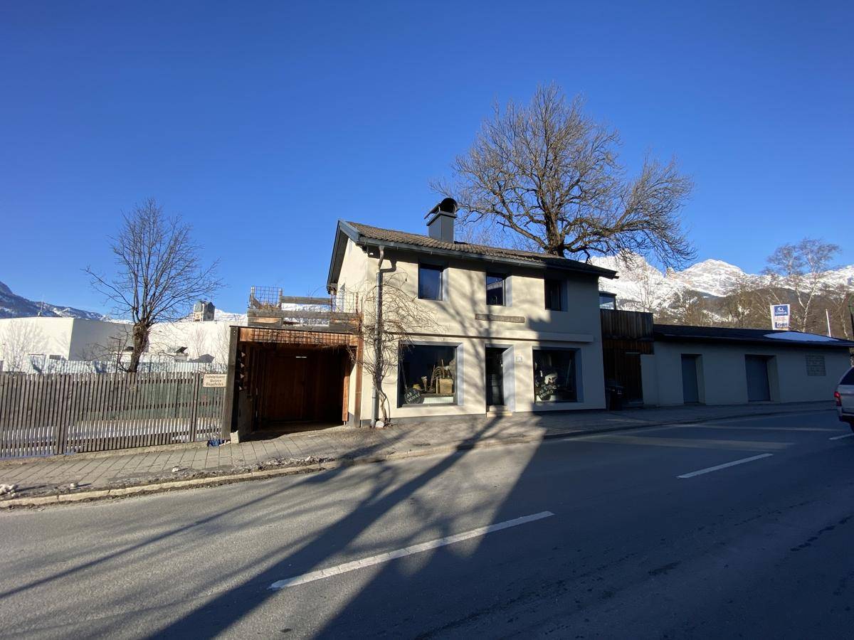 Weitwinkelansicht des Gebäudes von der Straße aus, mit Bergen und blauem Himmel.