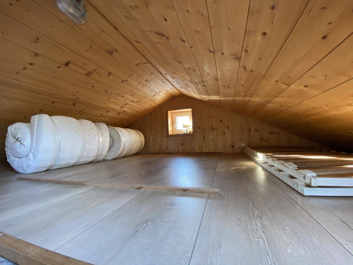 Gemütlicher Dachbodenbereich mit Holzverkleidung, Dachfenster und hellem Laminatboden.