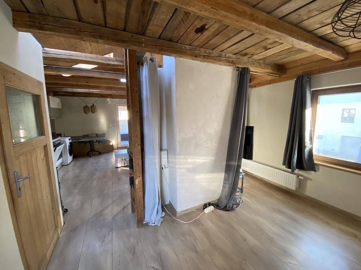 Heller Flur mit Holzbalkendecke und Laminatboden, der zu weiteren Räumen im Obergeschoss führt.